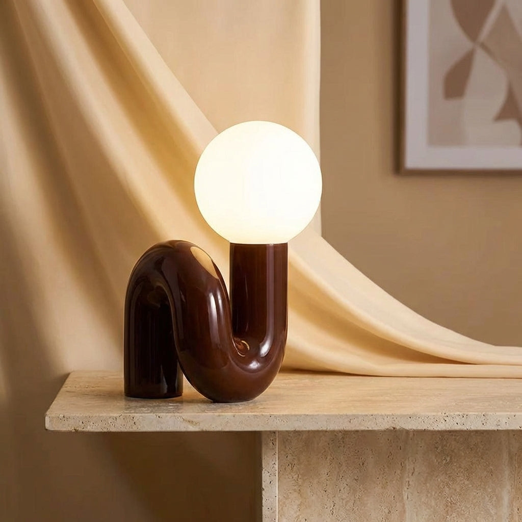 Skulpturel bordlampe med resinbase og kugle i matteret glas