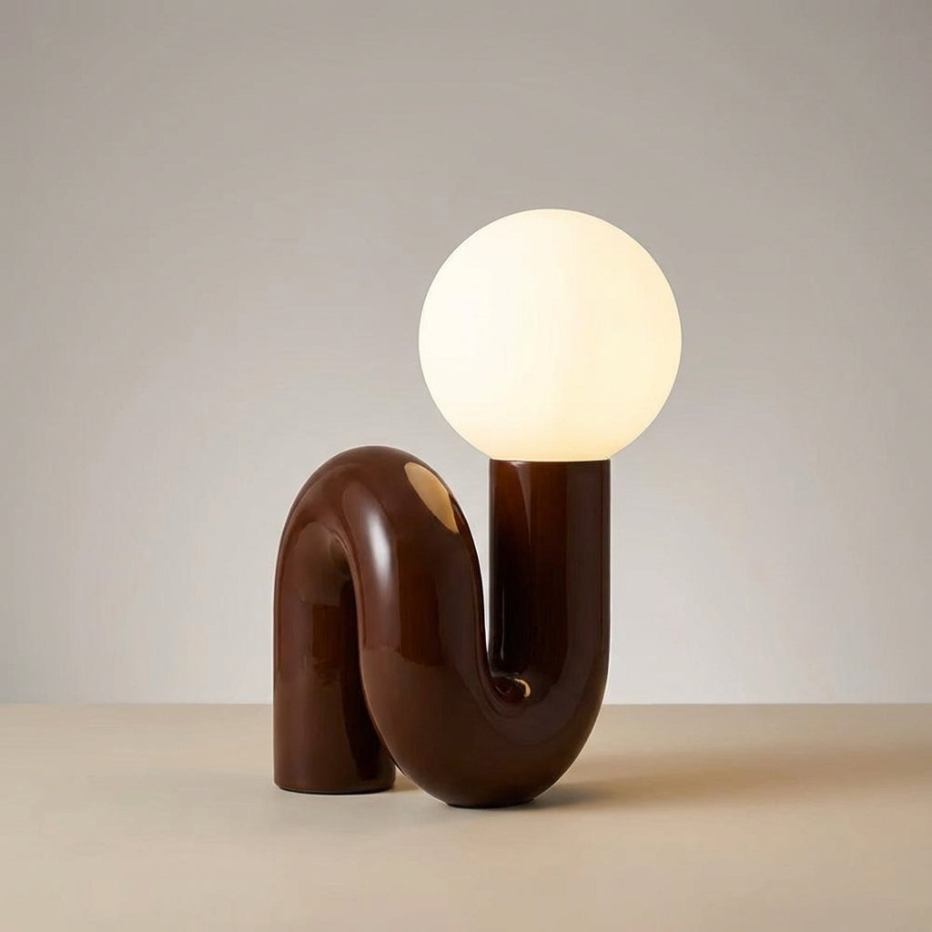 Skulpturel bordlampe med resinbase og kugle i matteret glas