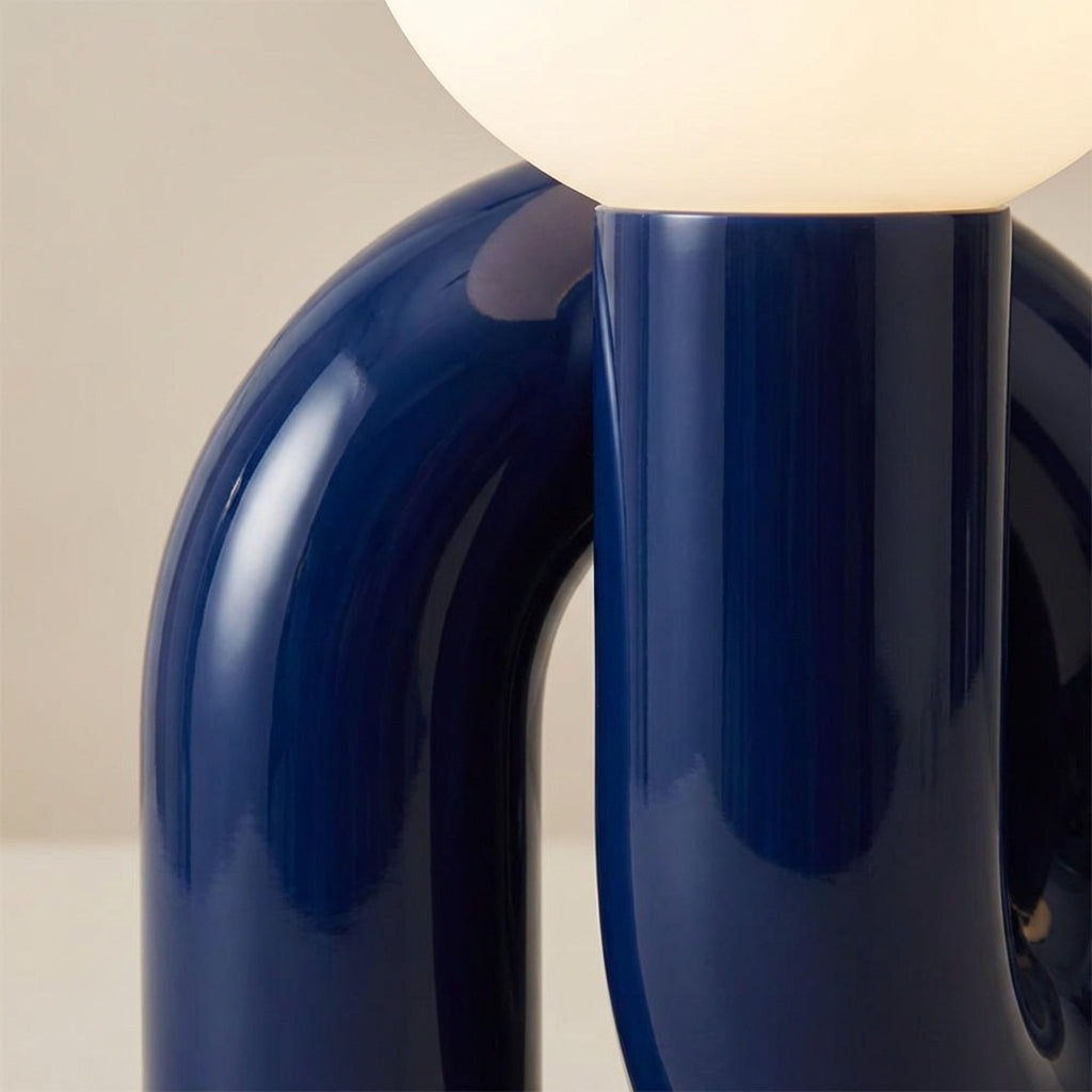 Skulpturel bordlampe med resinbase og kugle i matteret glas