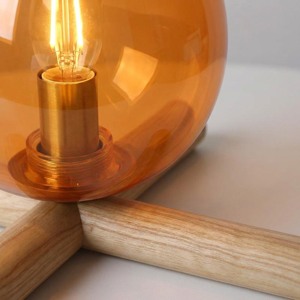 Minimalistische Tischlampe mit tropfenförmigem Glasschirm, Holzsockel und flackerndem Flammenlicht