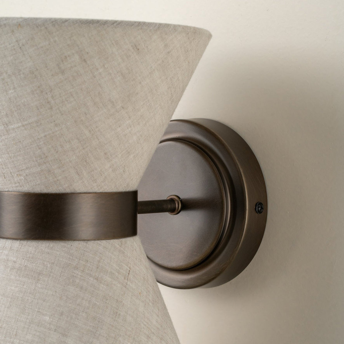 Klassisch-moderne Wandleuchte mit gealtertem Bronze-Finish und Leinenschirm